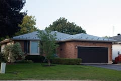 Single-storey ranch-style brick home with a low-hip Interlock aluminum slate roof in Colonial Brown, featuring snow guards and a double dark garage door.