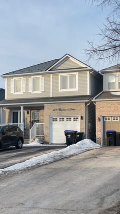 Two-storey suburban home at 142 Maplewood Drive, Angus ON, with black Interlock aluminum slate metal roofing on a medium-pitch gable, tan vinyl siding, and brick facade.