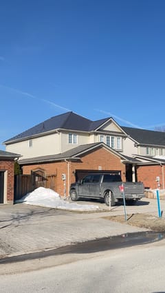 Two-storey brick home in Collingwood, ON with a complex hip roof clad in Interlock Tudor Brown aluminum slate roofing under a clear blue winter sky.
