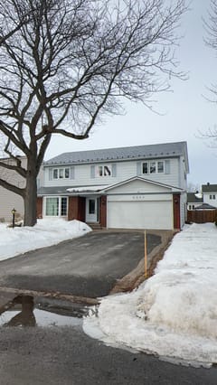 Two-storey colonial-style home in Orleans ON with Interlock charcoal grey aluminum slate metal roofing, brick lower facade, and attached garage.