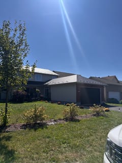 Two-storey suburban home with Interlock black aluminum slate metal roofing across multi-hip profiles, brick and vinyl siding, Ottawa ON.