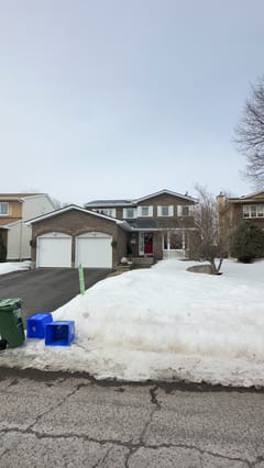 Two-storey brick home in Orleans ON with Interlock deep charcoal aluminum slate metal roof, double garage, shot from across snowy street.