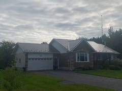 Ranch-style brick home in Winchester ON featuring Interlock Tudor Brown aluminum slate metal roofing with multi-gable complex roof profile under overcast skies.