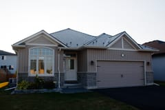 Single-family ranch-style home in Belleville ON with Interlock Tudor Brown aluminum slate metal roofing featuring multi-hip complex roof profile and stone accent base.