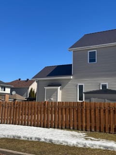 Tudor Brown Interlock aluminum slate metal roof on a two-storey suburban home in Ottawa, viewed from rear-left with a wooden fence in the foreground.