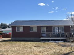Front elevation of a brick ranch home in Chesterville, ON featuring a black Interlock aluminum slate metal roof with a low-pitch simple gable and front deck.