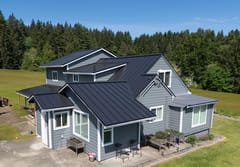 Black Interlock Standing Seam aluminum roof on a two-storey home with a black metal roof in a forested, Warren, Oregon