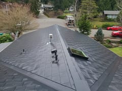 Aerial view of a complex hip roof clad in Interlock black aluminum slate tiles, featuring a skylight and vent pipes, on a suburban home in Redmond, WA.