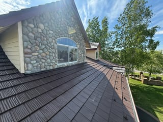 A ranch-style home with a brown metal roof and a stone accent wall.