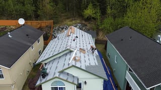 A metal roof being installed on a green house with a satellite dish on the roof