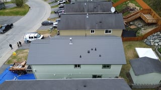 Modern home with light green siding and grey metal roof