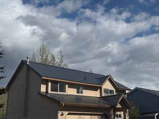 A modern-style single-family home with a finished metal roof under an overcast sky.