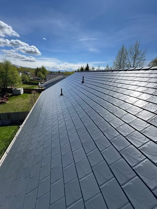 A modern metal roof in a suburban setting with lush greenery.