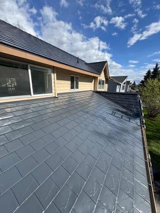A modern metal roof in a blue-grey colour installed by Interlock on a suburban home.