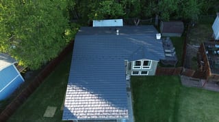 A metal roof on a craftsman style single-family home in a suburban setting.