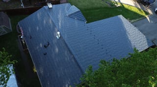 Aerial view of a ranch-style home with a metal roof and a chimney.
