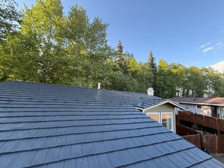 A ranch-style house with a metal roof in a suburban setting.