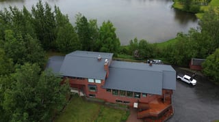 Aerial view of a modern metal roof on a single-family home in a forested setting.