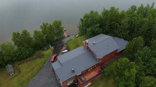 A large red colonial home with a gray metal roof and a gray ridge cap.