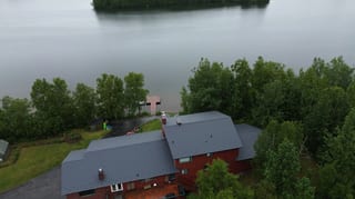 Aerial view of a red brick house with a grey metal roof
