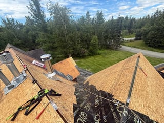 A house with a metal roof under construction in a forested area