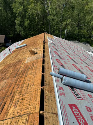 A metal roof under construction in a forested area.