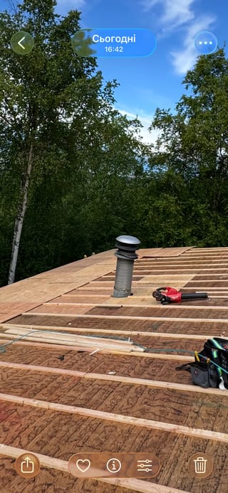 Metal roof being installed on a modern single-family home in a forested area with lush greenery
