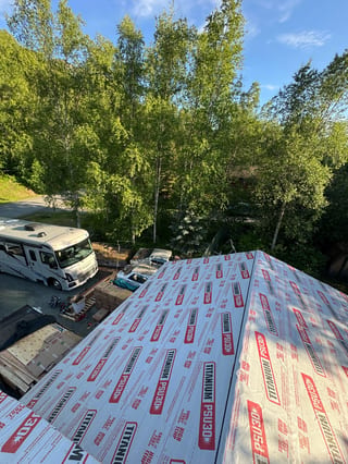 Metal roof under construction with white underlayment and red and black labels