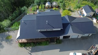 Aerial view of a modern single-family home with a black metal roof