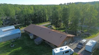 Aerial view of a ranch style home with a brown metal roof and a white RV parked in the driveway.