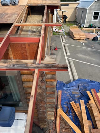 Metal roof installation in progress on a single-family craftsman-style home in an urban-suburban setting.