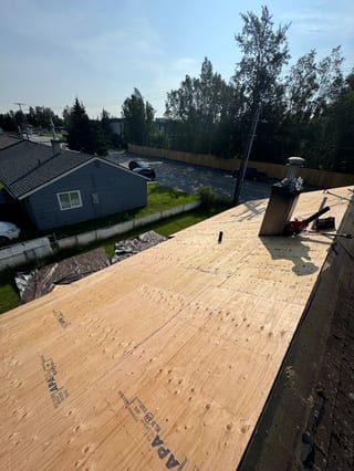 A suburban house with a partially installed metal roof and a blue sky