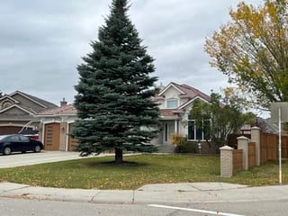 Aged Copper Interlock Shake aluminum roof on a grey two-storey home with dormers and a metal roof in an, Calgary, Alberta