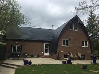 Black Interlock Slate aluminum roof on a red brick A-frame house with a black metal roof in a, Whitecourt, Alberta
