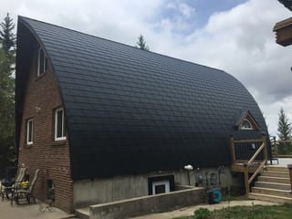 Black Interlock Slate aluminum roof on a brown chalet with a metal roof in a forested area, Whitecourt, Alberta