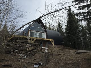 Black Interlock Slate aluminum roof on a brown A-frame home with a black metal roof in a forest, Whitecourt, Alberta
