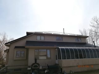 Black Interlock Tile aluminum roof on a tan single-storey home with a metal roof in rural Alberta, Redcliff, Alberta