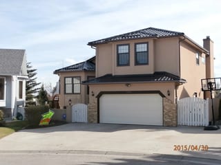 Black Interlock Tile aluminum roof on a beige two-storey home with a metal roof and a white fence, Calgary, Alberta