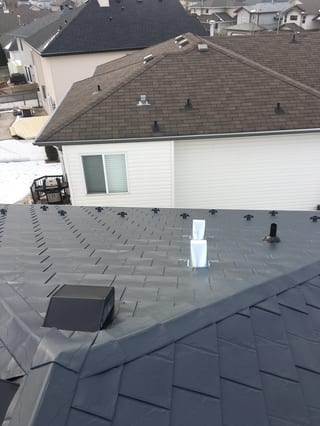 Deep Charcoal Interlock Slate aluminum roof on a white ranch style home with a chimney among snow covered, Fort Saskatchewan, Alberta