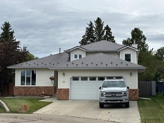 Tudor Brown Interlock Slate aluminum roof on a Tudor-style house with a brown roof in a rural area, Devon, Alberta