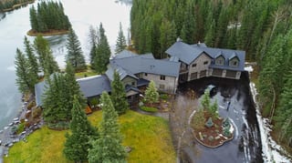 Black Interlock Shake aluminum roof on a brown chalet-style home among tall trees, Bragg Creek, Alberta