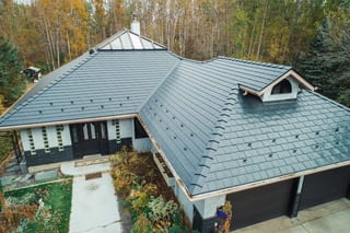 Black Interlock Slate aluminum roof on a white house with black metal roof in a wooded area, Spruce Grove, Alberta