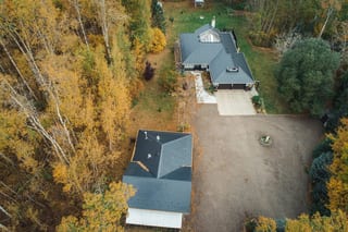 Black Interlock Slate aluminum roof on a black ranch home with a metal roof among tall trees, Spruce Grove, Alberta