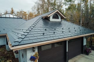 Black Interlock Slate aluminum roof on a black single-family home with dormers among tall trees, Spruce Grove, Alberta