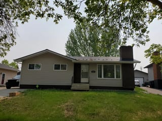 Black Interlock Slate aluminum roof on a brown single-storey home with a chimney among tall trees, Fort Saskatchewan, Alberta