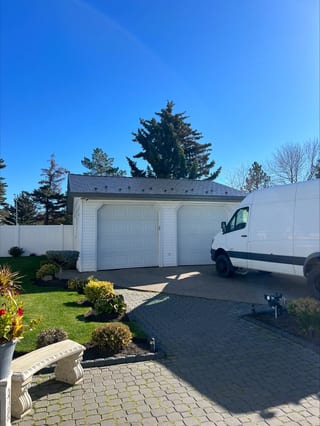 Deep Charcoal Interlock Slate aluminum roof being installed on a white single-family home with a grey roof in a rural, Edmonton, Alberta