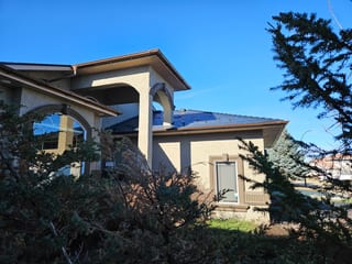 Black Interlock Slate aluminum roof on a single-storey home with a metal roof among trees, Red Deer, Alberta