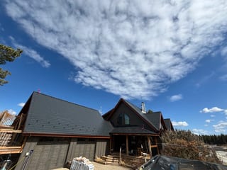 Black Interlock Slate aluminum roof on a brown, one-storey chalet with a gabled roof in a forested, Wildwood, Alberta
