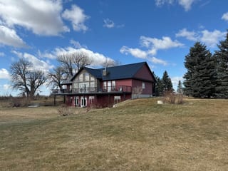 Black Interlock Slate aluminum roof on a red single-family modern home with a metal roof in a, Gem, Alberta