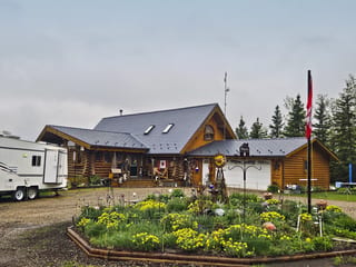 Log cabin-style home in rural Alberta with Interlock deep charcoal cedar shingle metal roof featuring skylights, dormers, and complex multi-plane roofline.